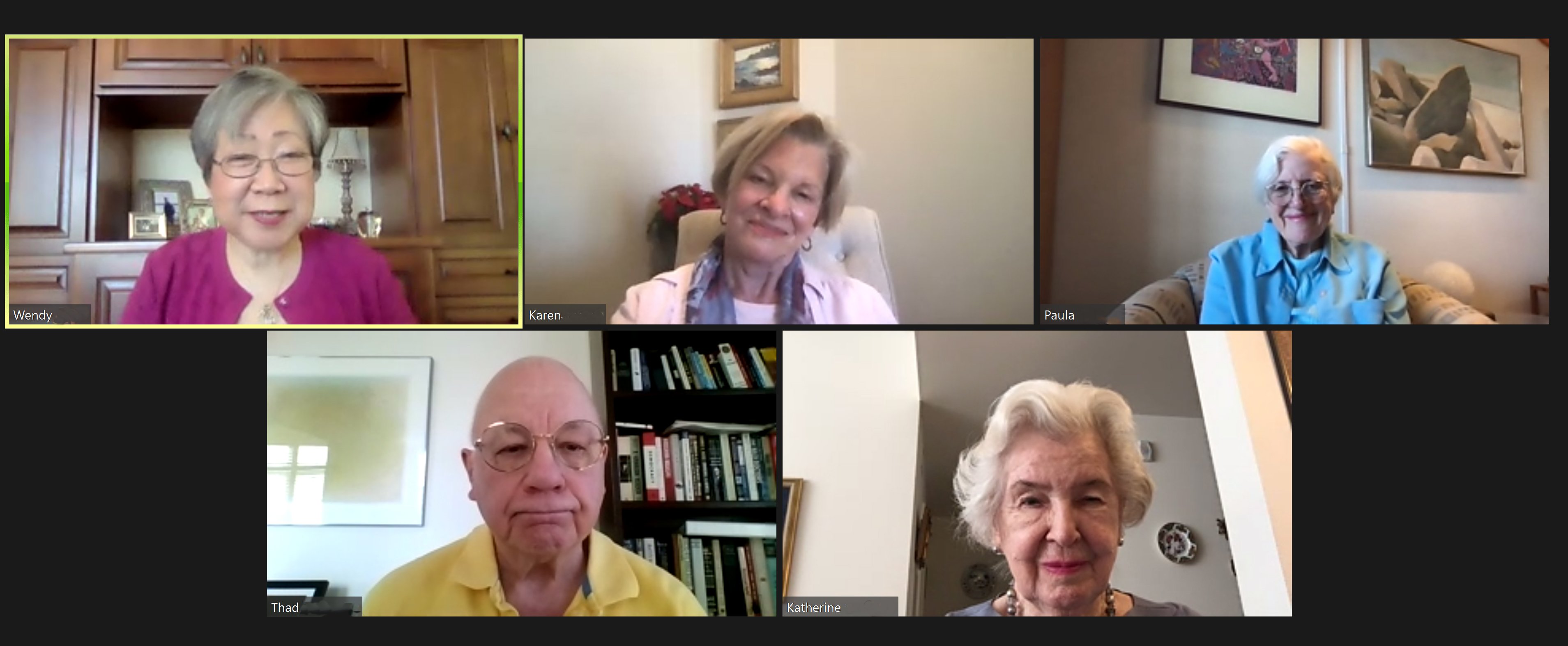 A screenshot of a Zoom video call with five older adults, three women and two men, smiling or looking content in their individual frames. Each person is in a different home setting.