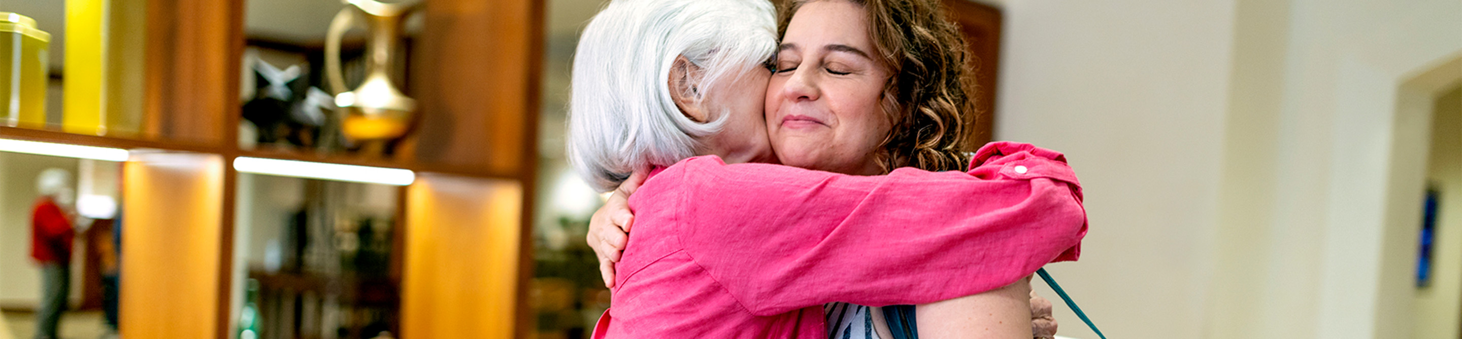 Two women embrace at a nonprofit senior living community.