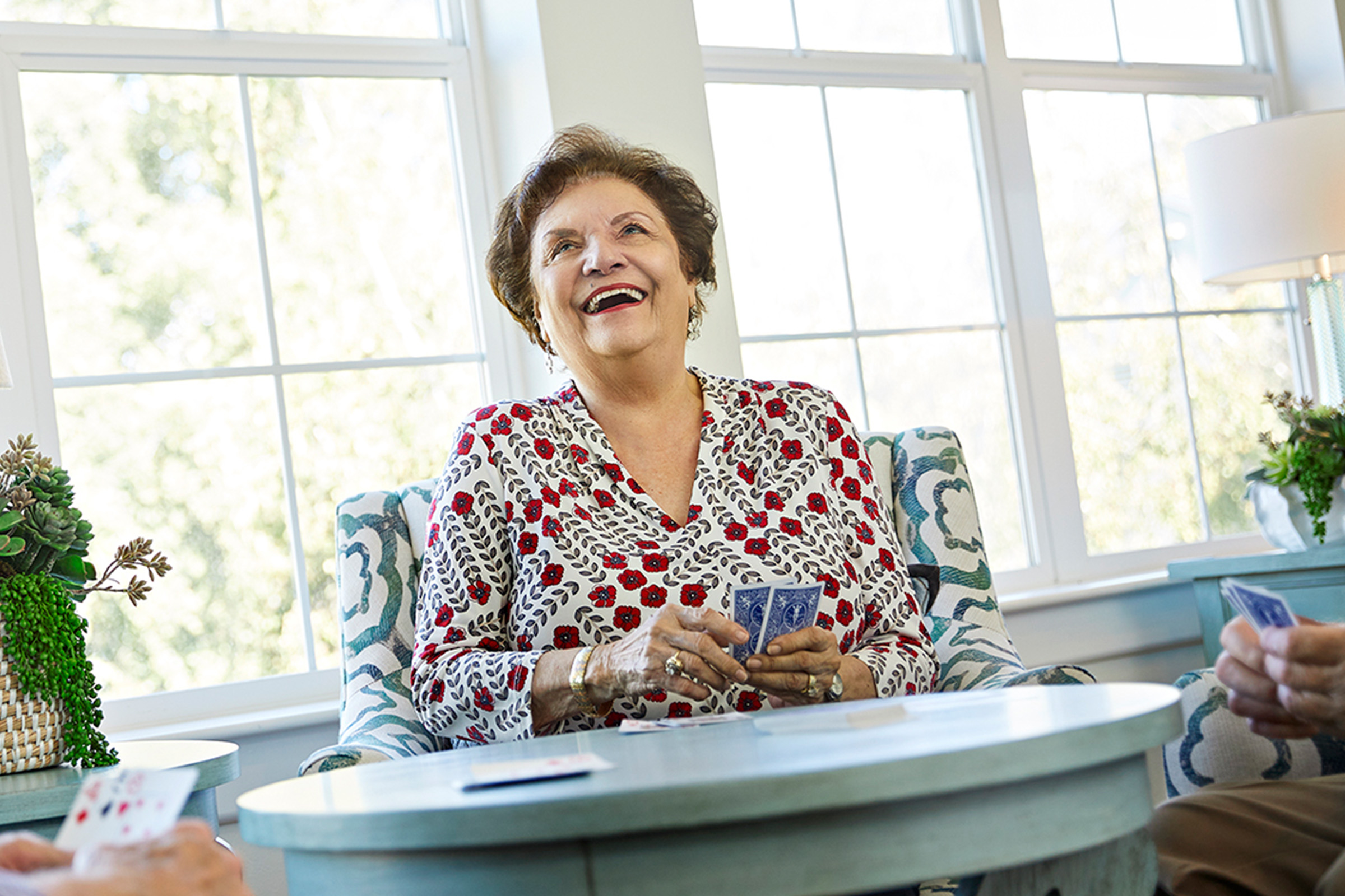 A smiling senior playing a card game at one of the best continuing care retirement communities in Orange County
