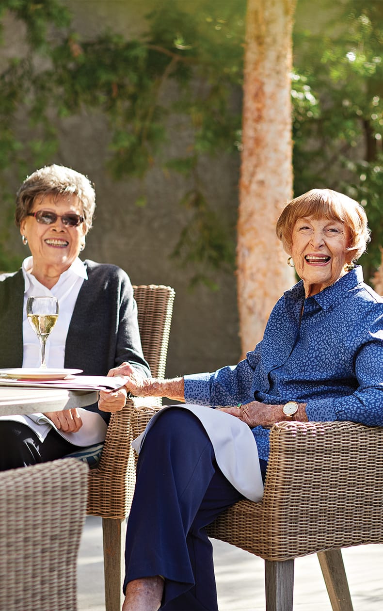Two smiling residents enjoy senior living in Los Angeles while dining outdoors