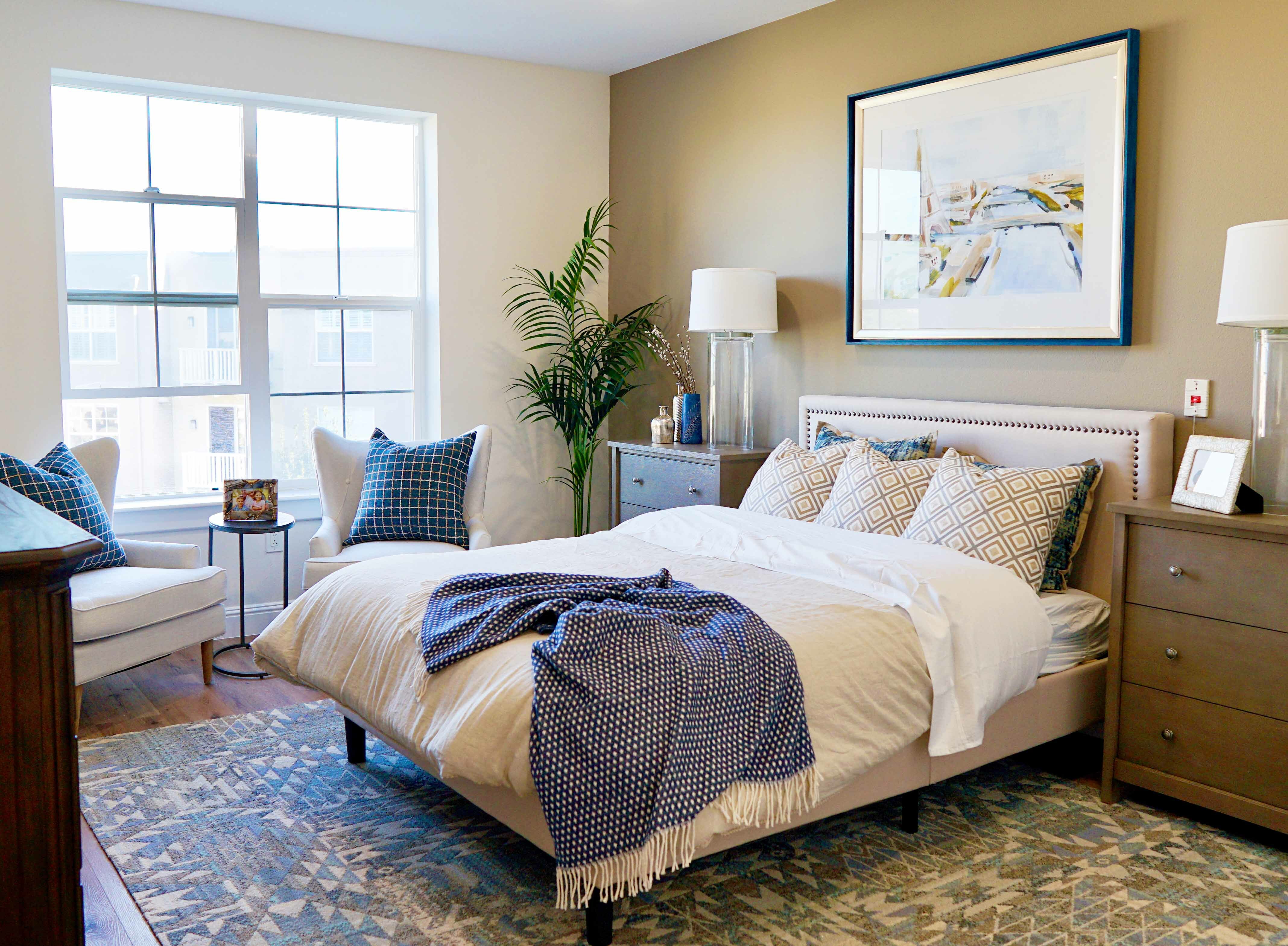 Bedroom with chairs, pillows, nightstands, and art