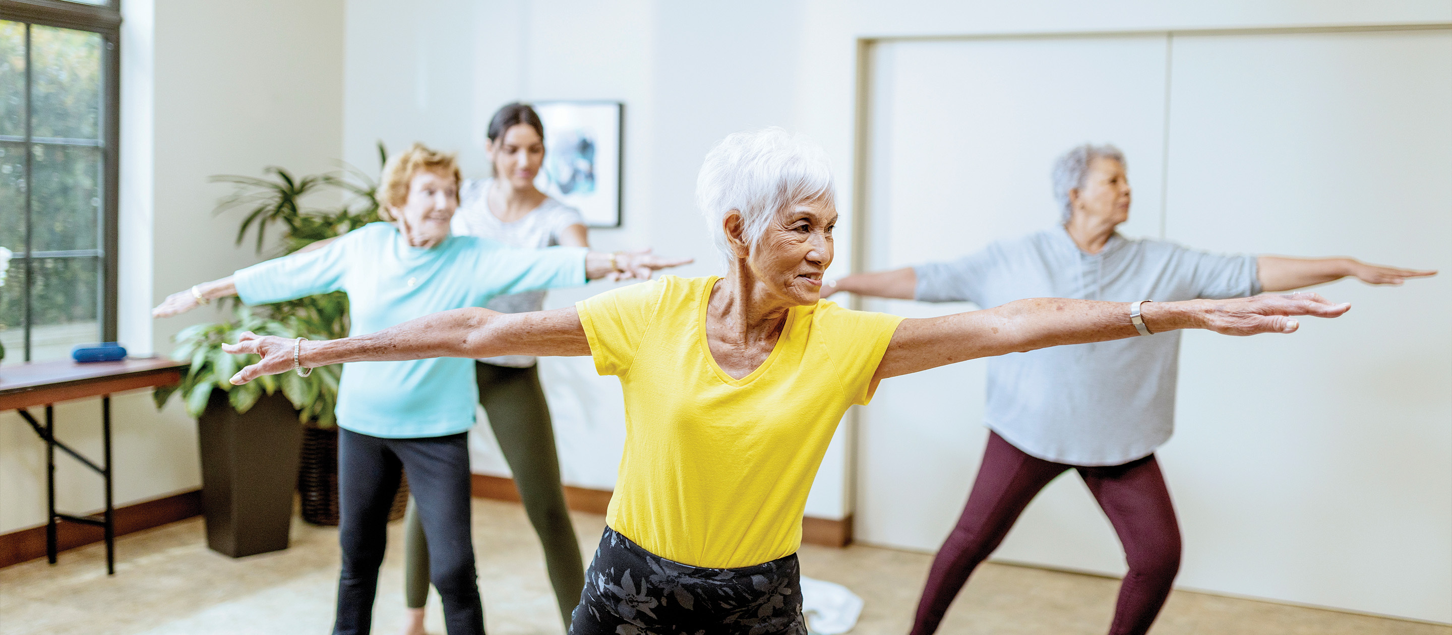 Three residents of one of our independent and assisting living communities practice yoga with an instructor