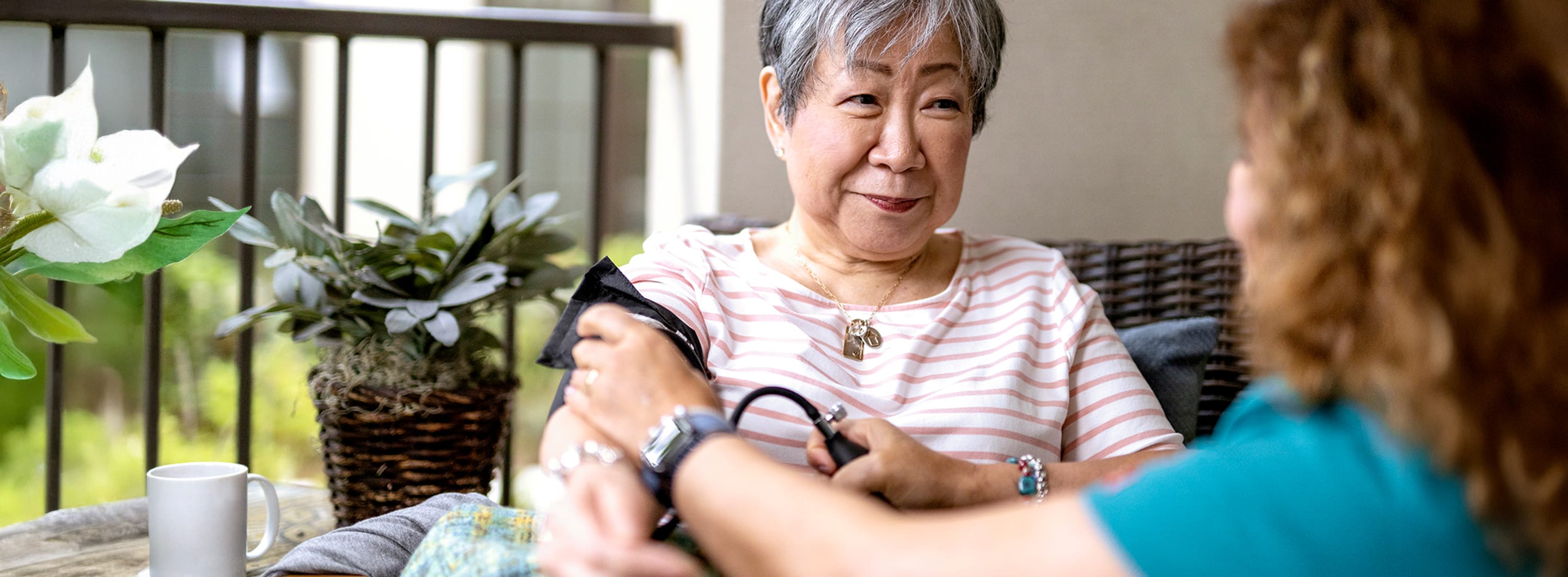 senior woman gets blood pressure checked by woman in blue shirt