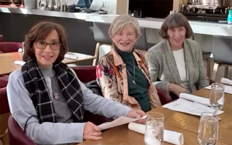 3 women sitting at breakfast table smiling