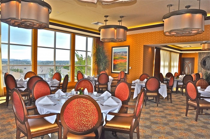 Luxury white linen dining room with a view of the Saddleback Mountains at our retirement community in Orange County.