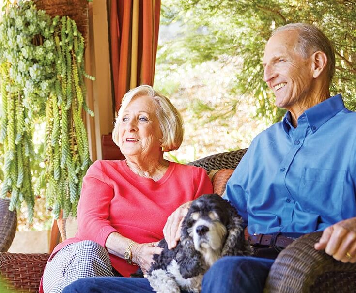 couple sitting outdoors with their dog