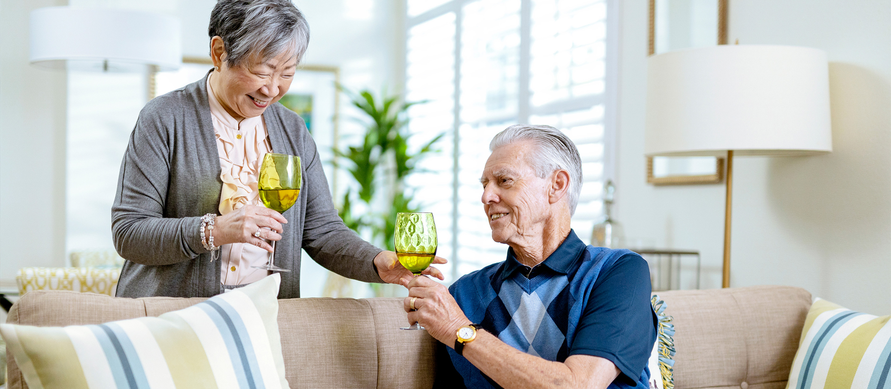 Two senior residents share a glass of wine at a continuing care retirement community