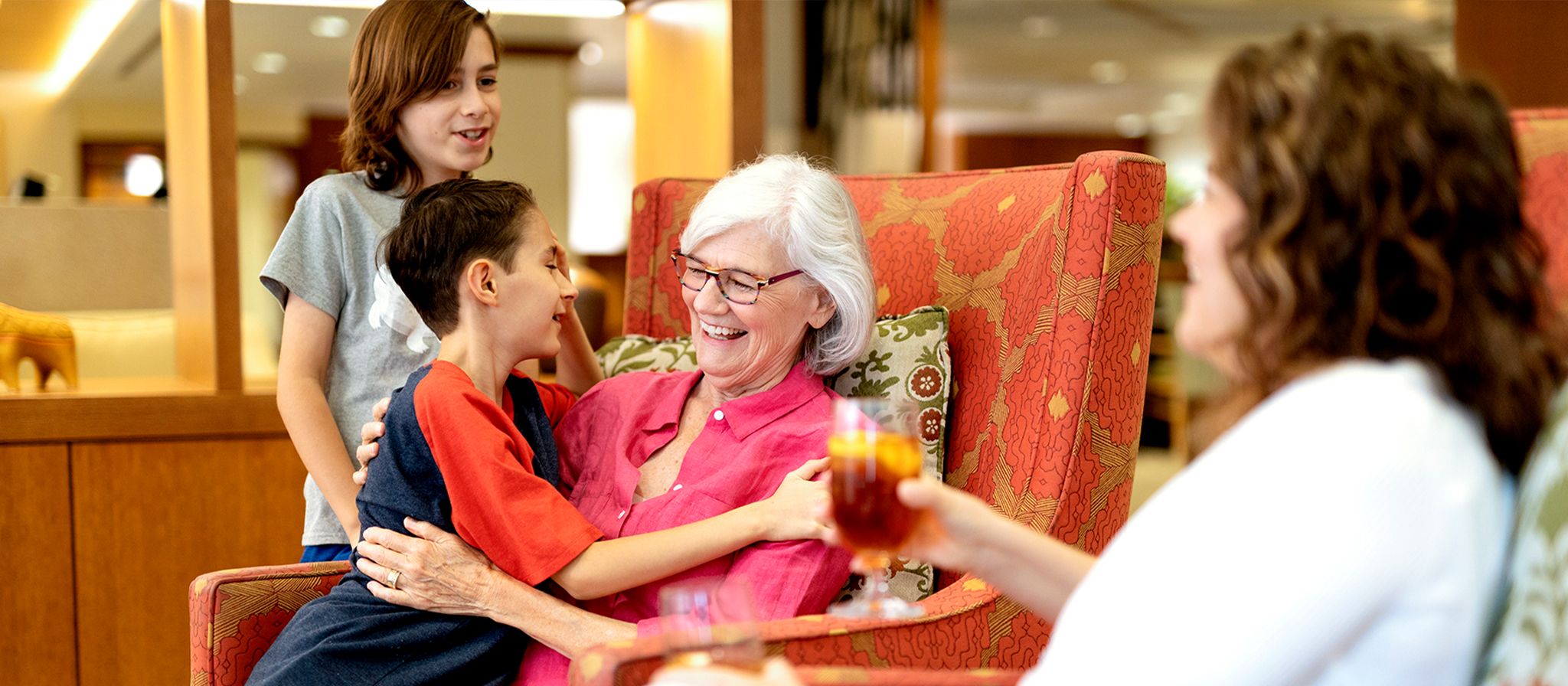 children hugging grandmother and smiling while sitting