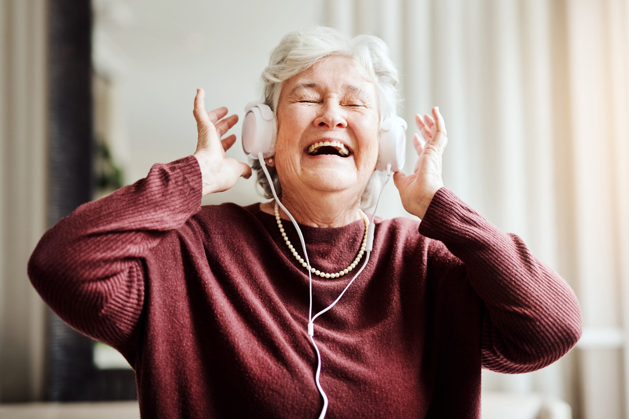 A female resident listens to headphones enjoying the best memory care Pasadena offers