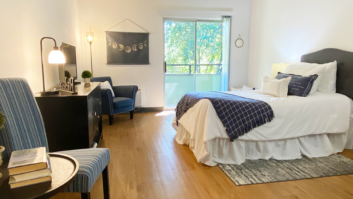apartment with bed, dresser, chairs, and sliding door to balcony