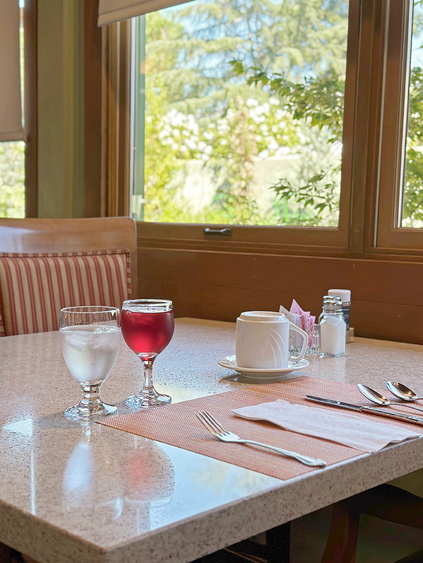table with drinks, silverware, and an outdoor view