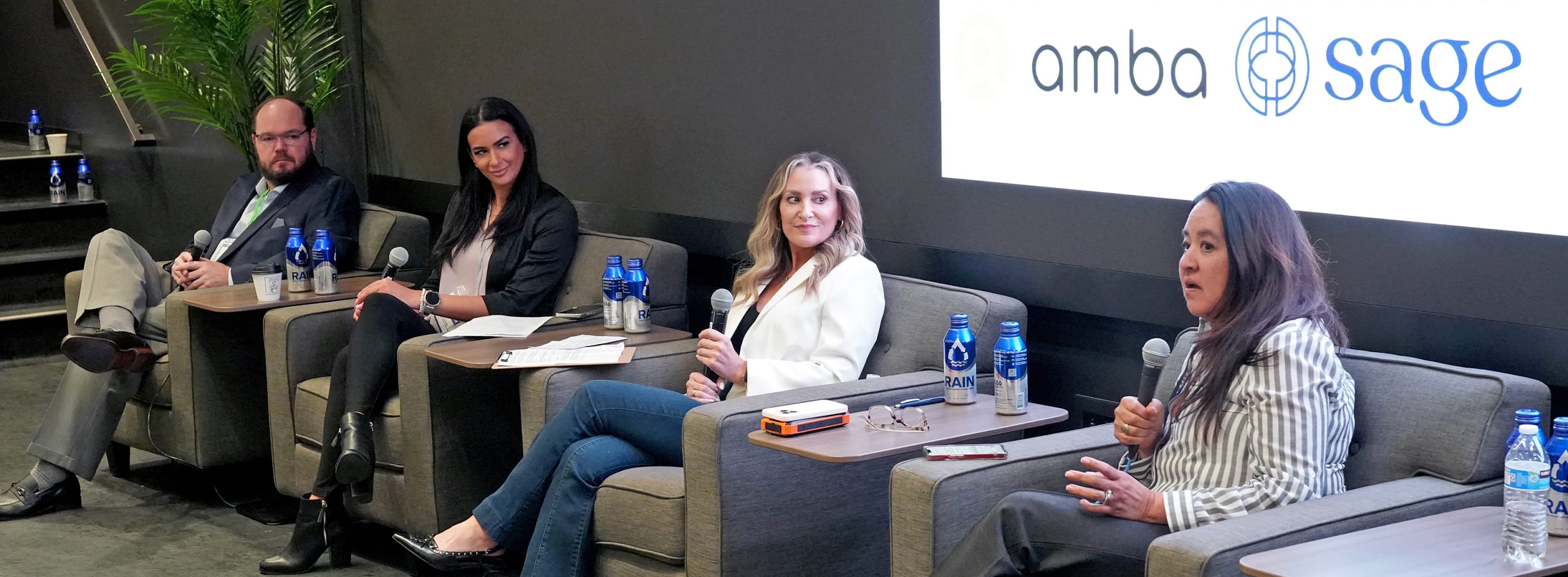 group of speakers sitting in lounge chairs with microphones