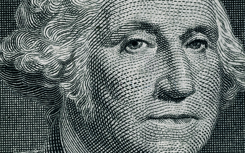Close-up of a detailed engraving of George Washingtons face from U.S. currency, showing fine lines and shading, curly hair, and a calm expression.