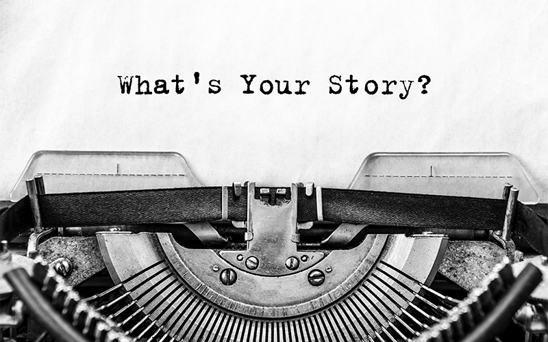 Close-up of a vintage typewriter with a sheet of paper showing the typed words Whats Your Story? in black ink.