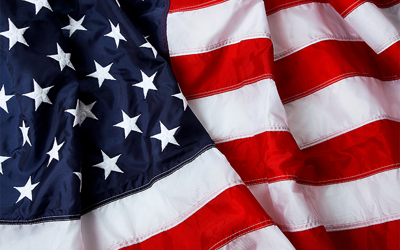 Close-up of the United States flag showing white stars on a blue field and alternating red and white stripes, with the fabric gently folded and rippled.